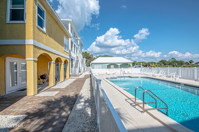 view of swimming pool featuring french doors and a patio area