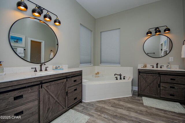 112 Riviera Dr, Panama City Beach, FL 32413 - bathroom featuring two vanities, wood finished floors, and a bath