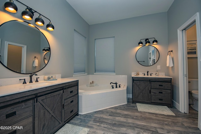 112 Riviera Dr, Panama City Beach, FL 32413 - bathroom featuring two vanities, wood finished floors, a garden tub, and toilet