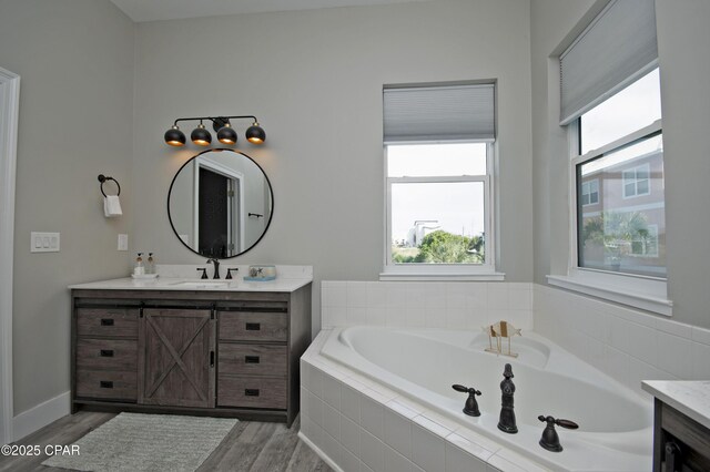 112 Riviera Dr, Panama City Beach, FL 32413 - bathroom with vanity, a garden tub, healthy amount of natural light, and wood finished floors