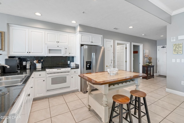 kitchen featuring light tile patterned flooring, sink, white cabinetry, backsplash, and white appliances