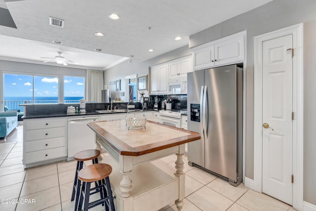 kitchen with white appliances, light tile patterned floors, a peninsula, and a healthy amount of sunlight