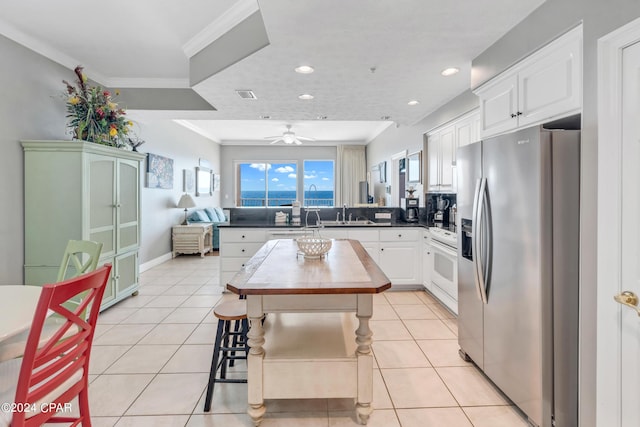 kitchen featuring stove, light tile patterned flooring, a peninsula, and stainless steel fridge with ice dispenser