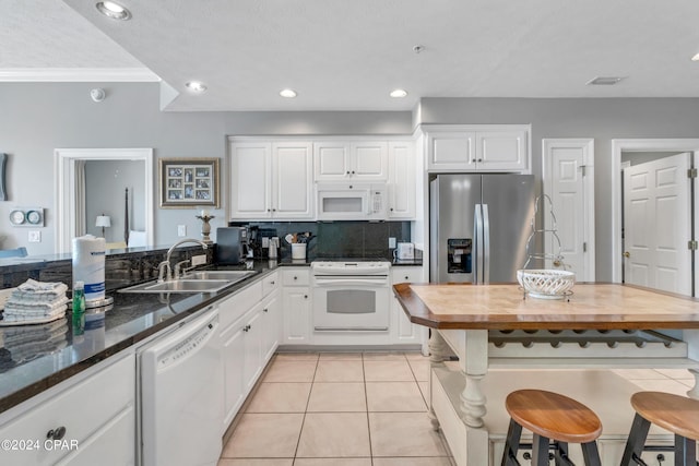 kitchen featuring light tile patterned floors, decorative backsplash, white cabinets, white appliances, and a sink