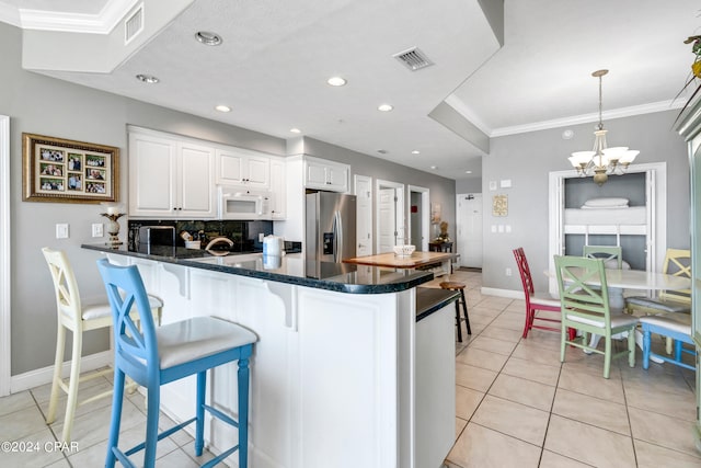 kitchen featuring stainless steel fridge with ice dispenser, tasteful backsplash, white cabinets, a kitchen breakfast bar, and decorative light fixtures