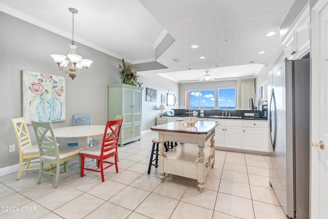 kitchen featuring ceiling fan with notable chandelier, white cabinetry, a kitchen island, light tile patterned floors, and stainless steel fridge