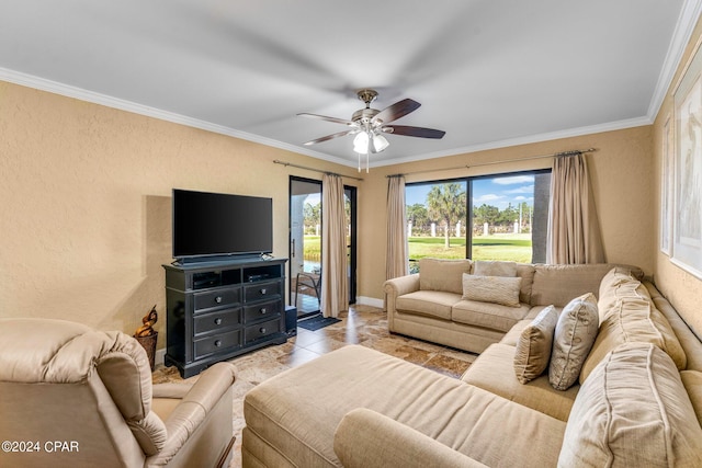 living area with a ceiling fan, light tile patterned flooring, a textured wall, baseboards, and ornamental molding