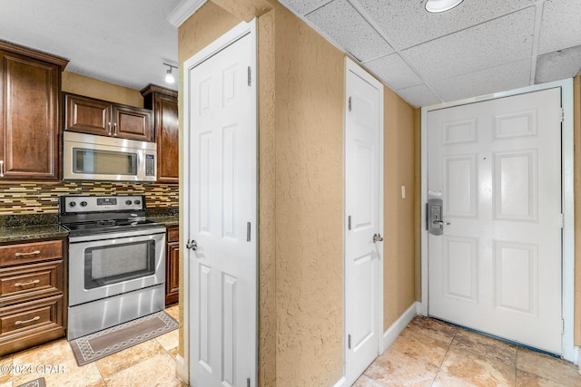 kitchen featuring backsplash, dark brown cabinets, appliances with stainless steel finishes, and baseboards