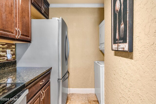 kitchen with dark stone countertops, light tile patterned floors, backsplash, and crown molding