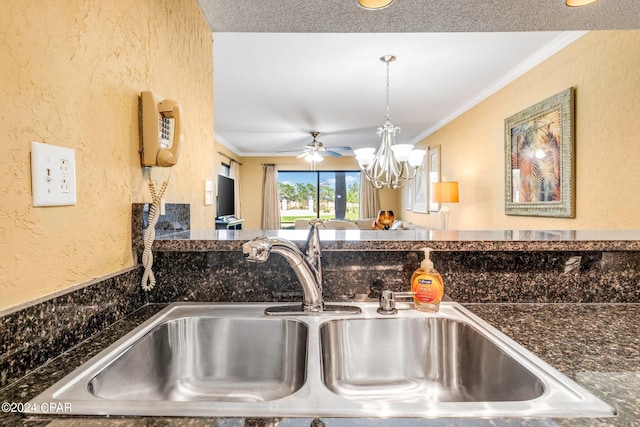 interior details with a sink, ceiling fan with notable chandelier, a textured wall, decorative light fixtures, and ornamental molding