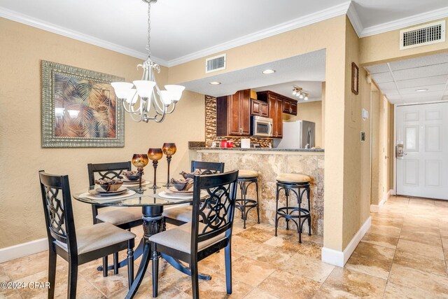 dining area with crown molding and an inviting chandelier