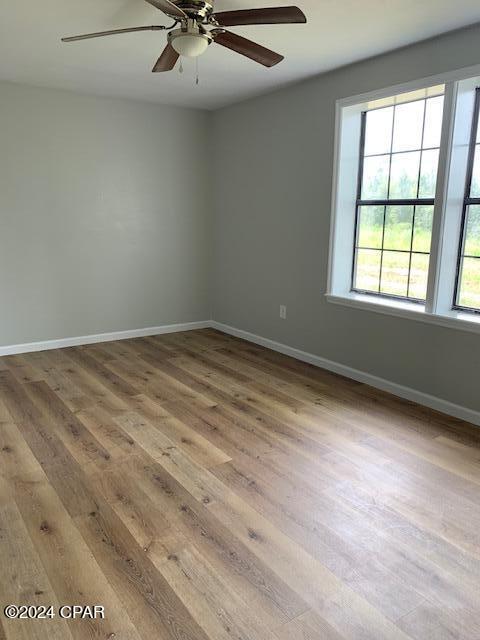 spare room with light wood-type flooring and ceiling fan