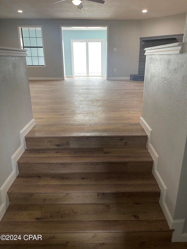 stairs with wood-type flooring, ceiling fan, and a healthy amount of sunlight