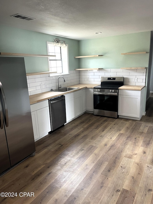 kitchen featuring white cabinetry, wood counters, sink, and stainless steel appliances