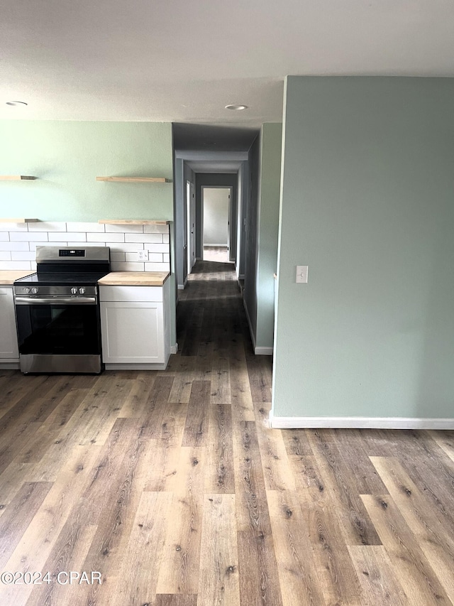 kitchen with light wood-type flooring, stainless steel range oven, backsplash, and white cabinets