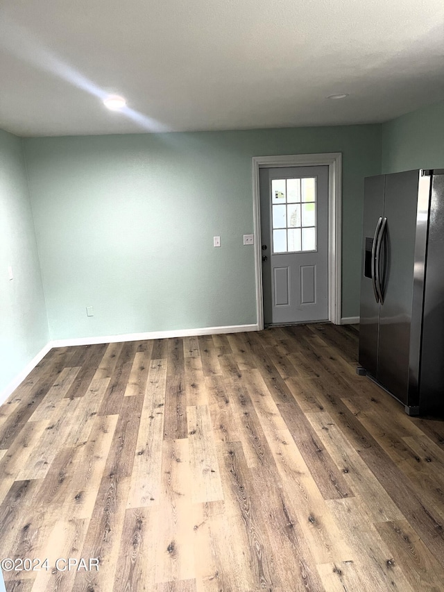 interior space with stainless steel refrigerator with ice dispenser and hardwood / wood-style flooring