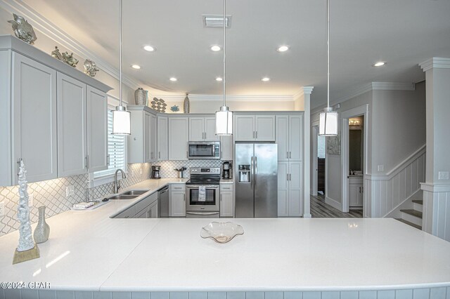 kitchen featuring crown molding, appliances with stainless steel finishes, hanging light fixtures, and sink