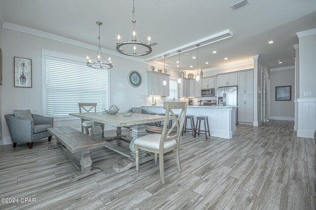 dining area with crown molding and light hardwood / wood-style floors