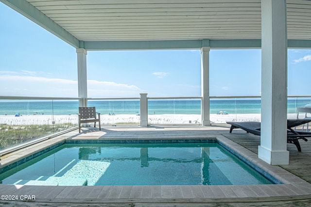 view of pool with a patio, a water view, and a beach view