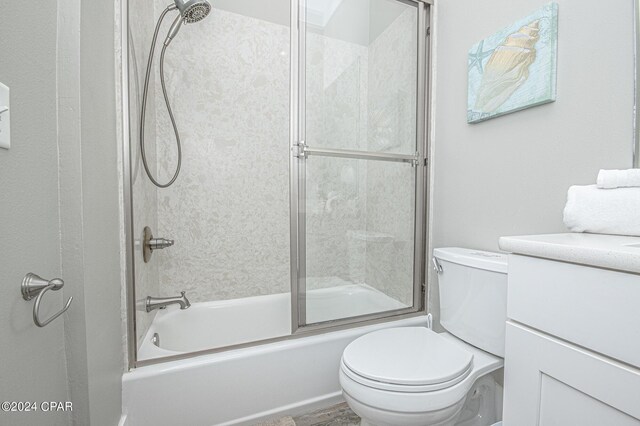 full bathroom with combined bath / shower with glass door, vanity, and toilet