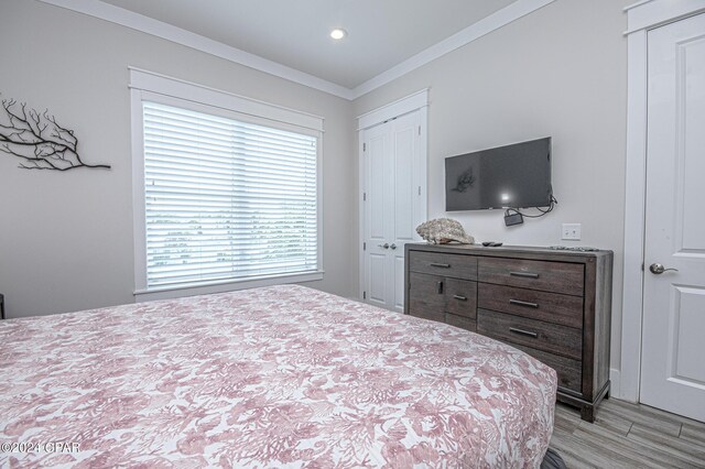 bedroom featuring ornamental molding, light hardwood / wood-style flooring, and a closet