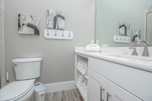 bathroom with wood-type flooring, vanity, and toilet