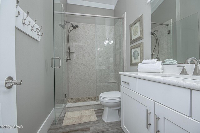 bathroom with hardwood / wood-style flooring, a shower with door, vanity, and toilet