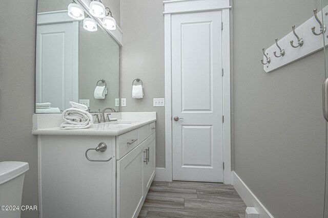 bathroom with wood-type flooring, vanity, and toilet