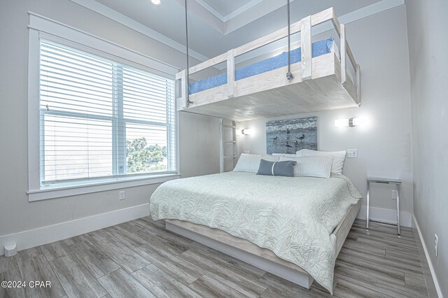 bedroom with hardwood / wood-style flooring, crown molding, and multiple windows