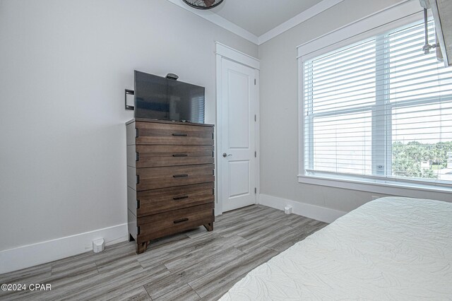 bedroom with crown molding and light hardwood / wood-style floors