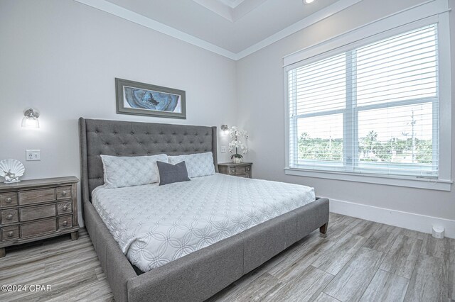 bedroom featuring multiple windows, ornamental molding, and hardwood / wood-style floors