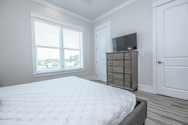 bedroom featuring light wood-type flooring and crown molding