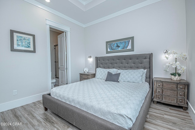 bedroom with light hardwood / wood-style flooring, crown molding, and ensuite bathroom