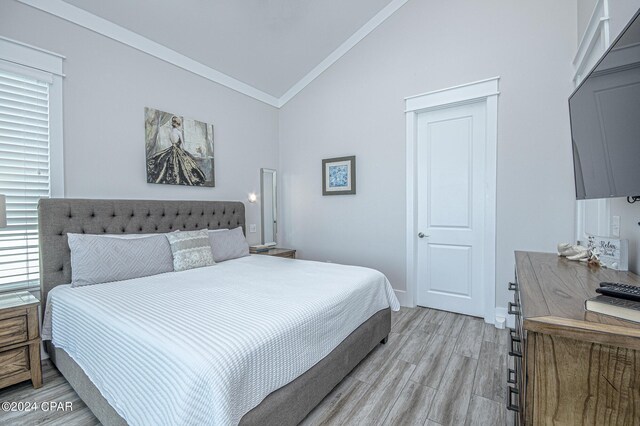 bedroom featuring crown molding, light hardwood / wood-style floors, and high vaulted ceiling