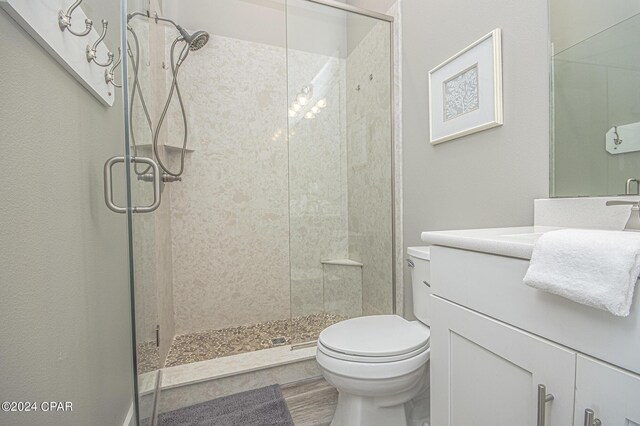 bathroom featuring wood-type flooring, vanity, toilet, and an enclosed shower