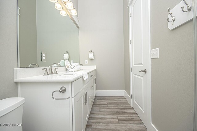 bathroom with wood-type flooring, vanity, and toilet