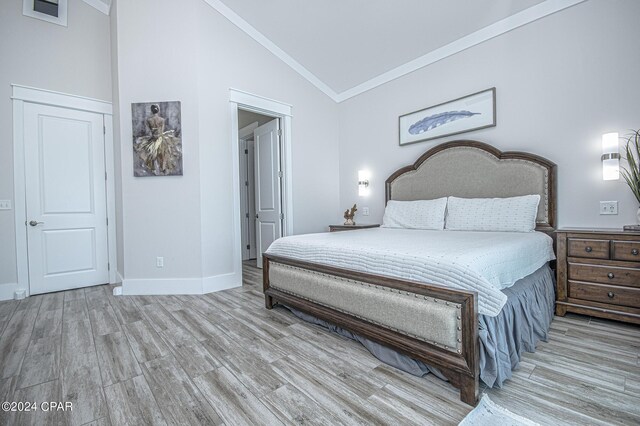 bedroom featuring ornamental molding, light hardwood / wood-style floors, and high vaulted ceiling