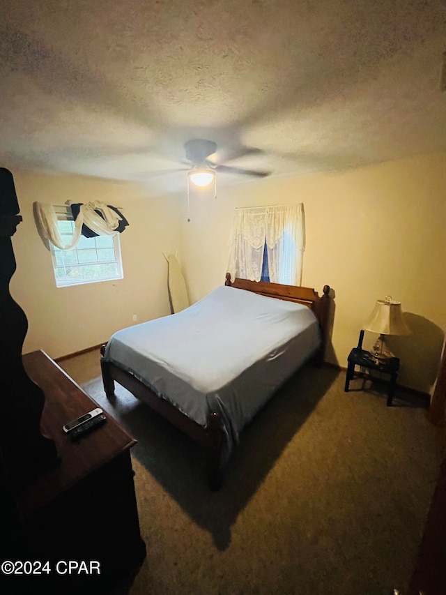 bedroom featuring ceiling fan, a textured ceiling, and dark colored carpet