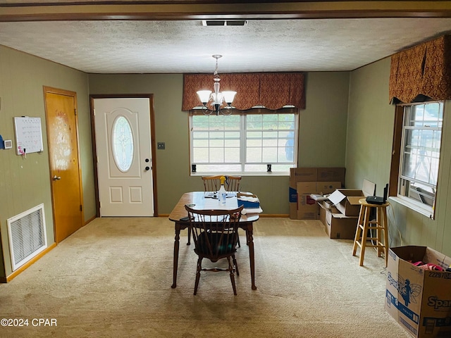 carpeted dining space featuring a textured ceiling and a chandelier