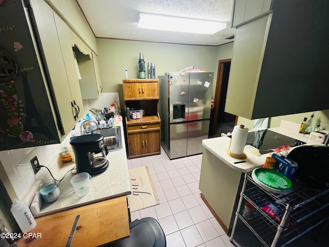 kitchen featuring tasteful backsplash, light tile patterned flooring, a textured ceiling, stainless steel refrigerator with ice dispenser, and sink