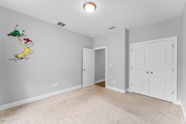 unfurnished bedroom featuring light carpet and a closet