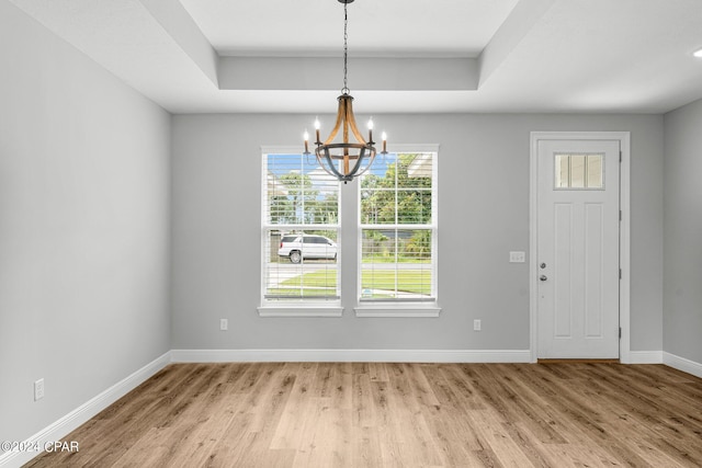 entryway featuring a raised ceiling, light hardwood / wood-style floors, and an inviting chandelier