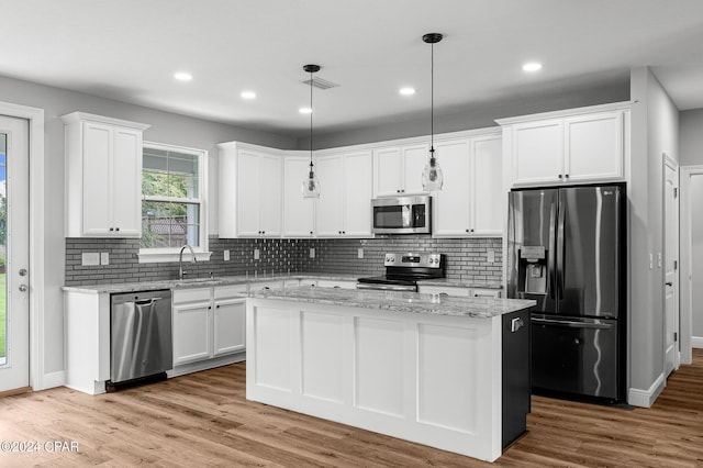 kitchen featuring pendant lighting, a kitchen island, stainless steel appliances, and white cabinetry