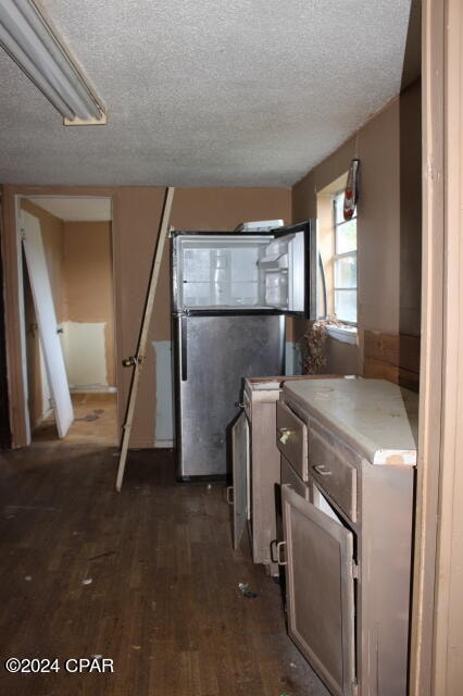 kitchen featuring stainless steel fridge, a textured ceiling, and dark hardwood / wood-style flooring