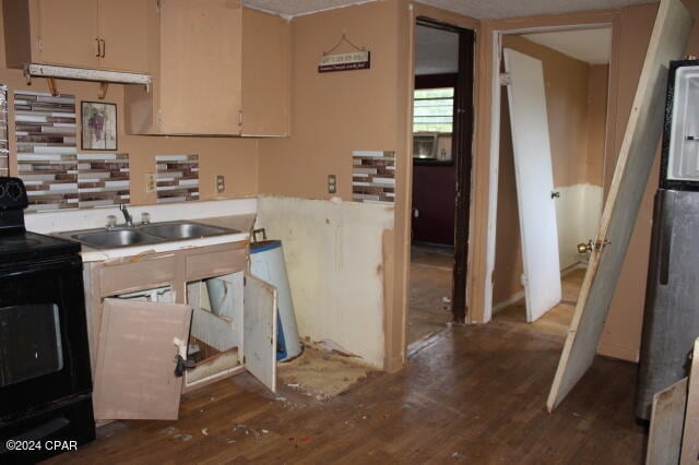 kitchen with stainless steel refrigerator, black / electric stove, dark wood-type flooring, and sink