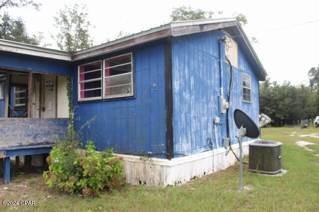 view of side of home with a lawn and central AC