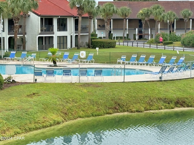 view of swimming pool featuring a water view and a lawn