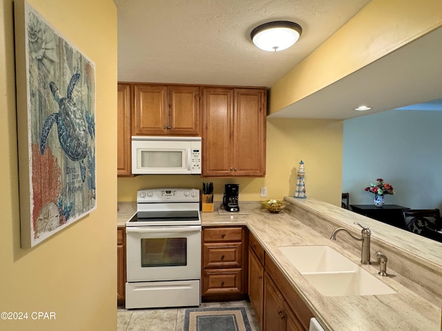 kitchen with light tile patterned floors, white appliances, kitchen peninsula, and sink