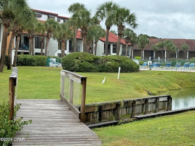 view of dock with a swimming pool and a lawn