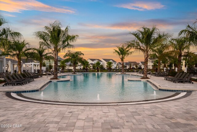 pool at dusk with pool water feature and a patio area